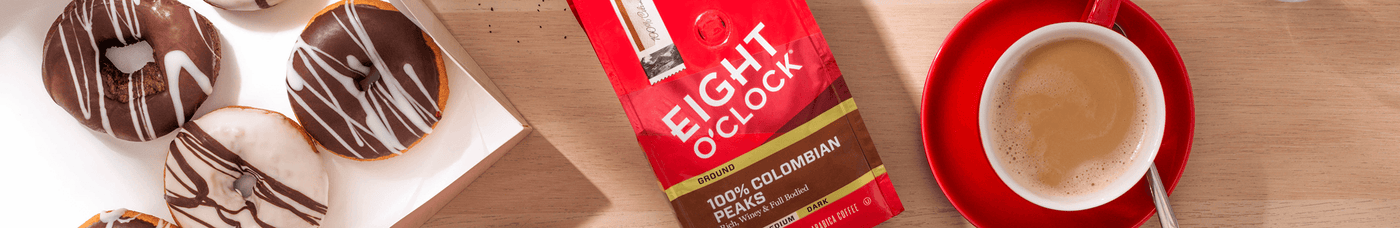 Eight O'clock coffee in coffee mugs with a bag of coffee bean, with sugar cubes and donuts.